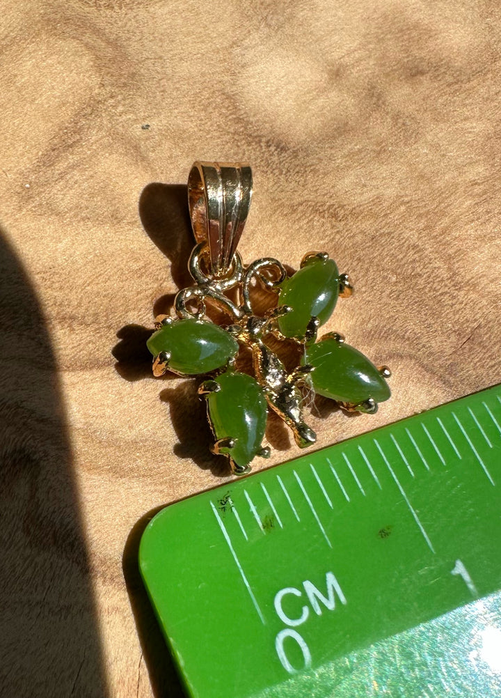 A grade vintage jade butterfly pendant with six green teardrop stones in a gold setting beside a centimeter scale.