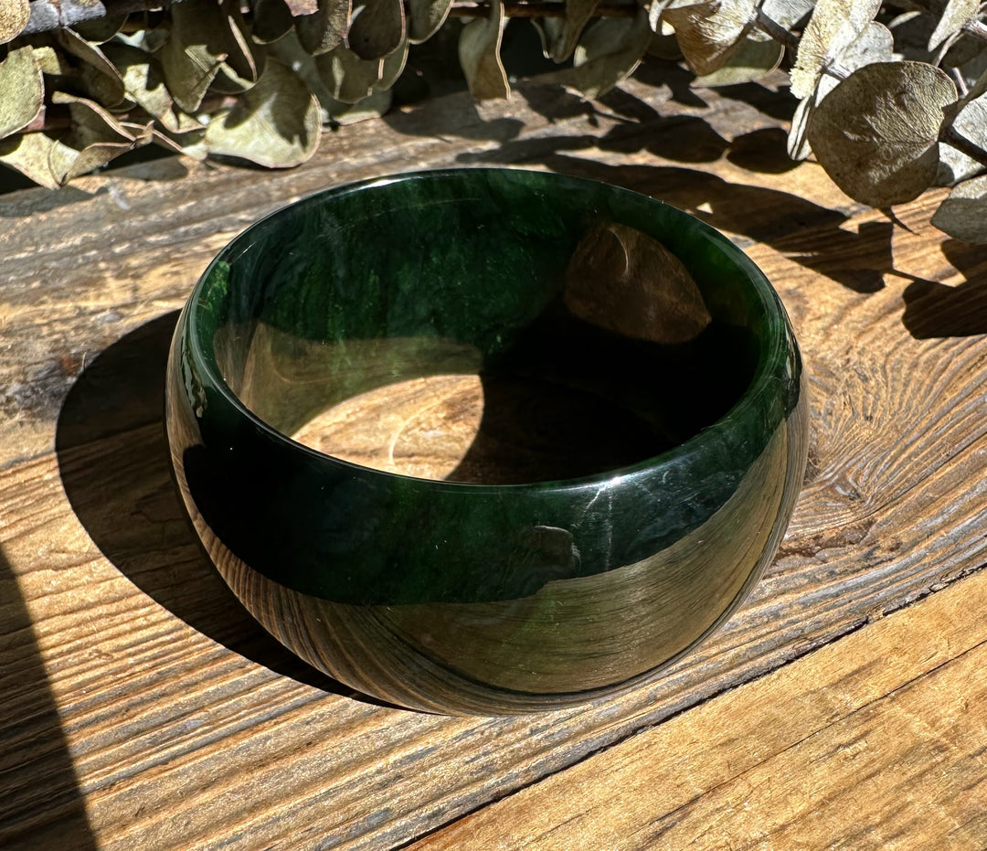 Top view of the dark green jade wide bangle showing its circular opening and polished exterior.
