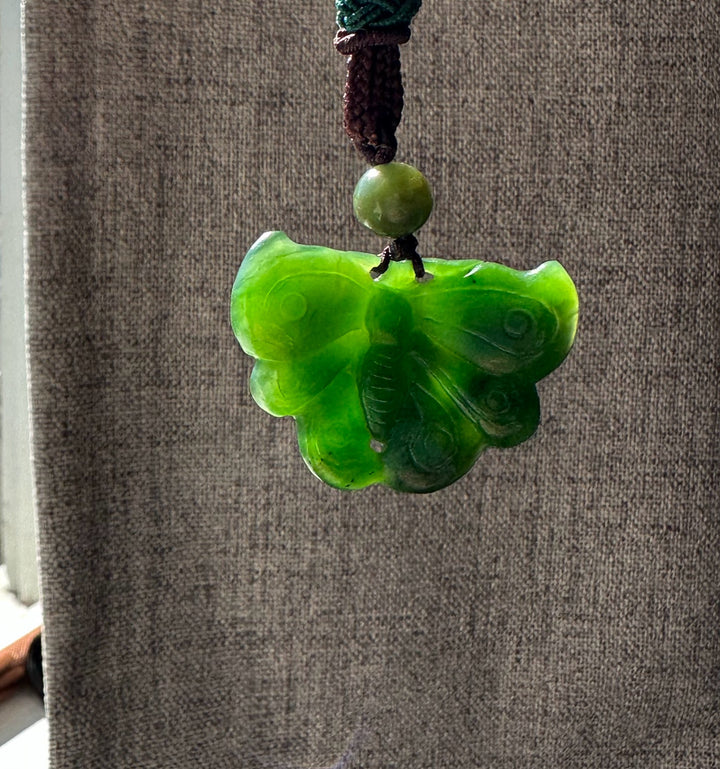 A Grade Ogden Jade Butterfly Pendant in bright green suspended from brown braided cord with a green bead