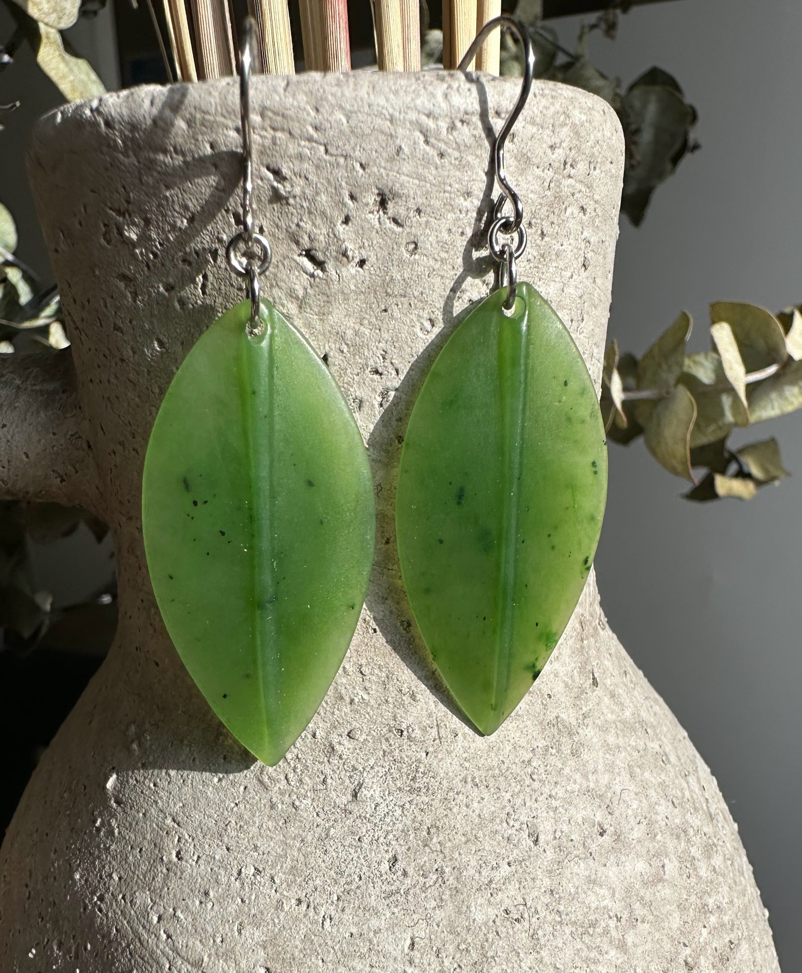 Pair of elongated jade leaf earrings with silver ear wires.