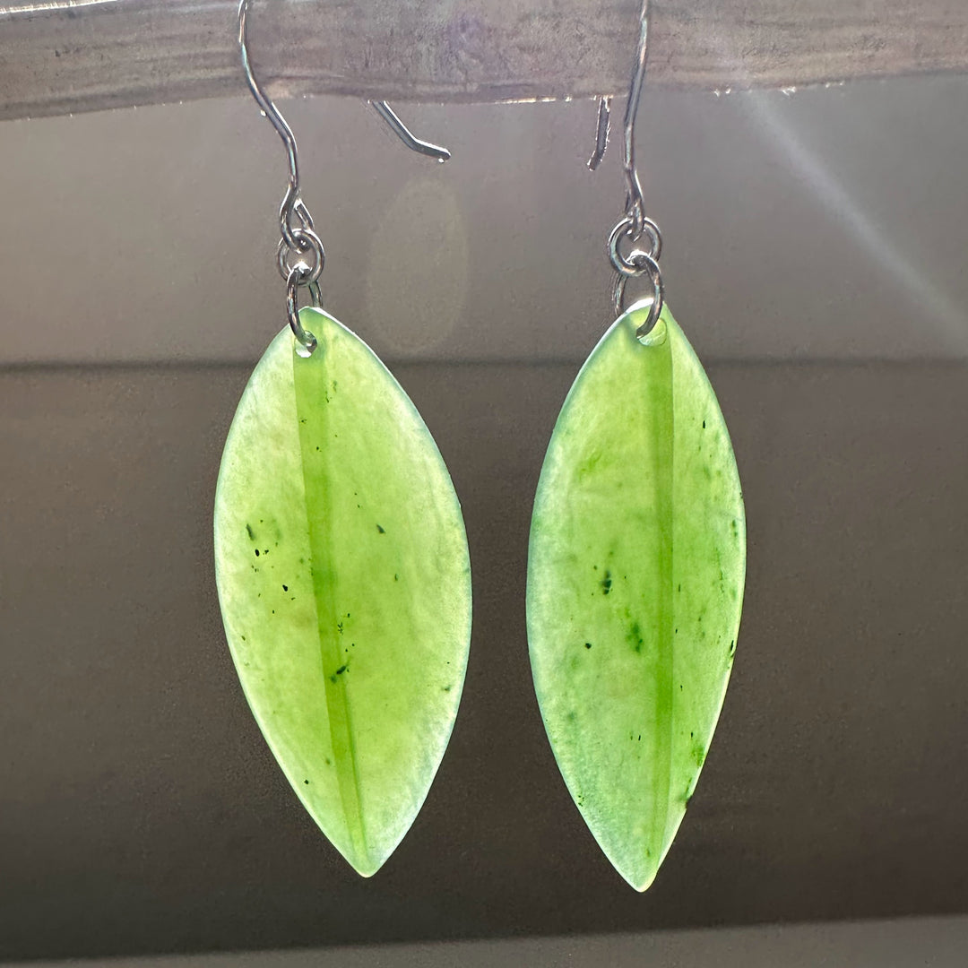 Pair of pale green jade leaf earrings with silver hooks, each elongated leaf showing a central vein.
