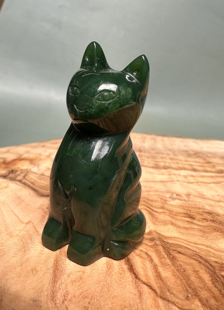 Canadian Jade Sitting Cat figurine in dark green jade on a wooden surface