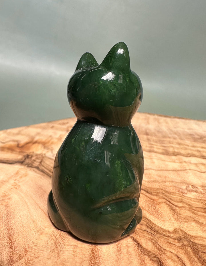 Dark green jade sitting cat sculpture viewed from the back.