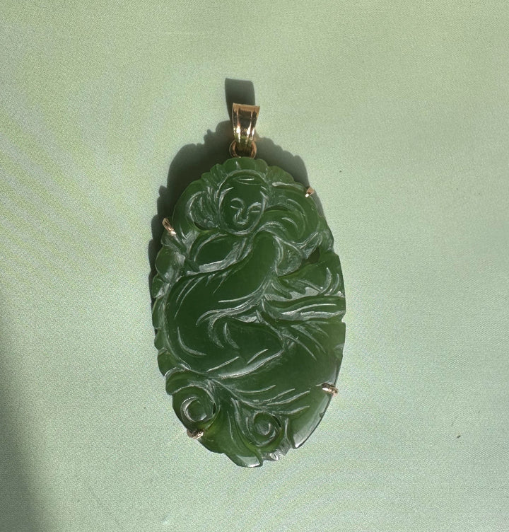 Emerald green jade Guanyin pendant with intricate swirling carving and gold bail