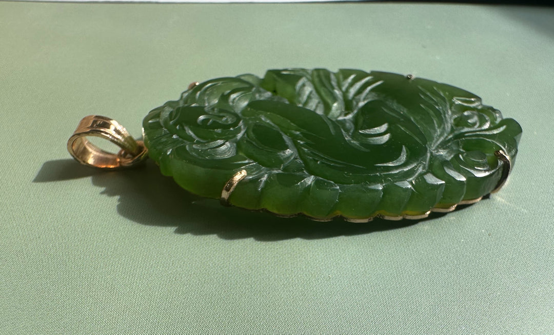 Side view of vintage jade Guanyin pendant showing ornate carved surface and gold bail
