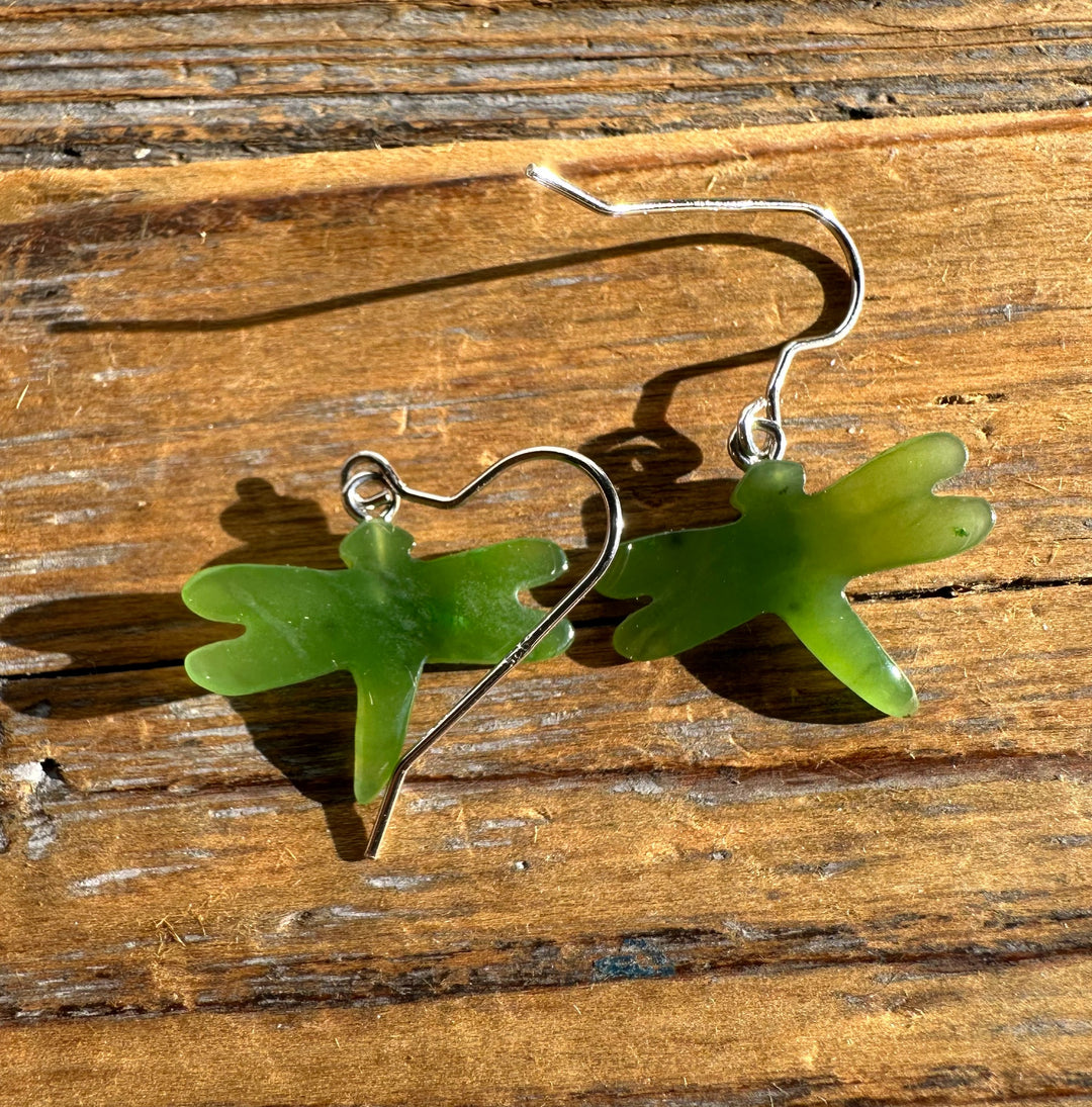 Green jade dragonfly earrings with silver hooks on a wooden surface