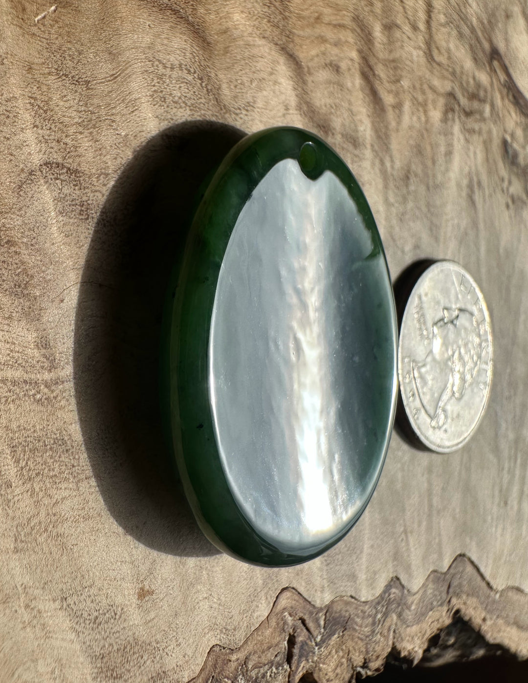 Green stone with a quarter for scale on a wooden surface