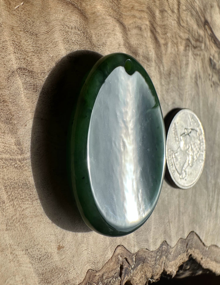 Green stone with a quarter for scale on a wooden surface