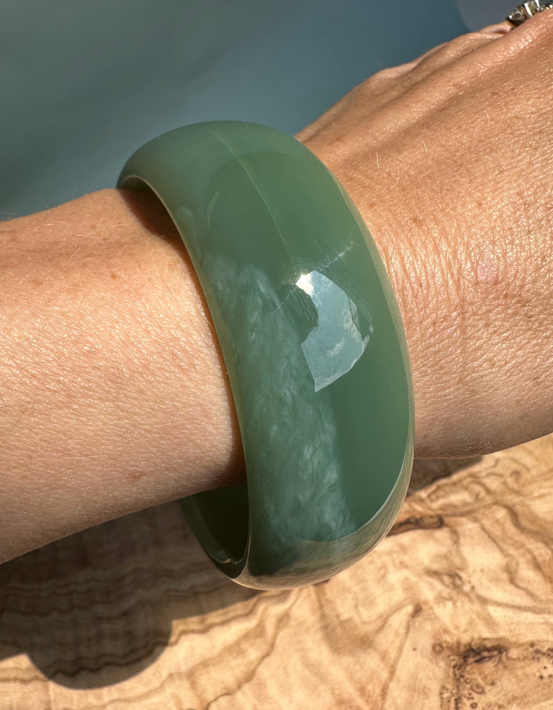 A green Siberian jade bangle worn on the wrist.