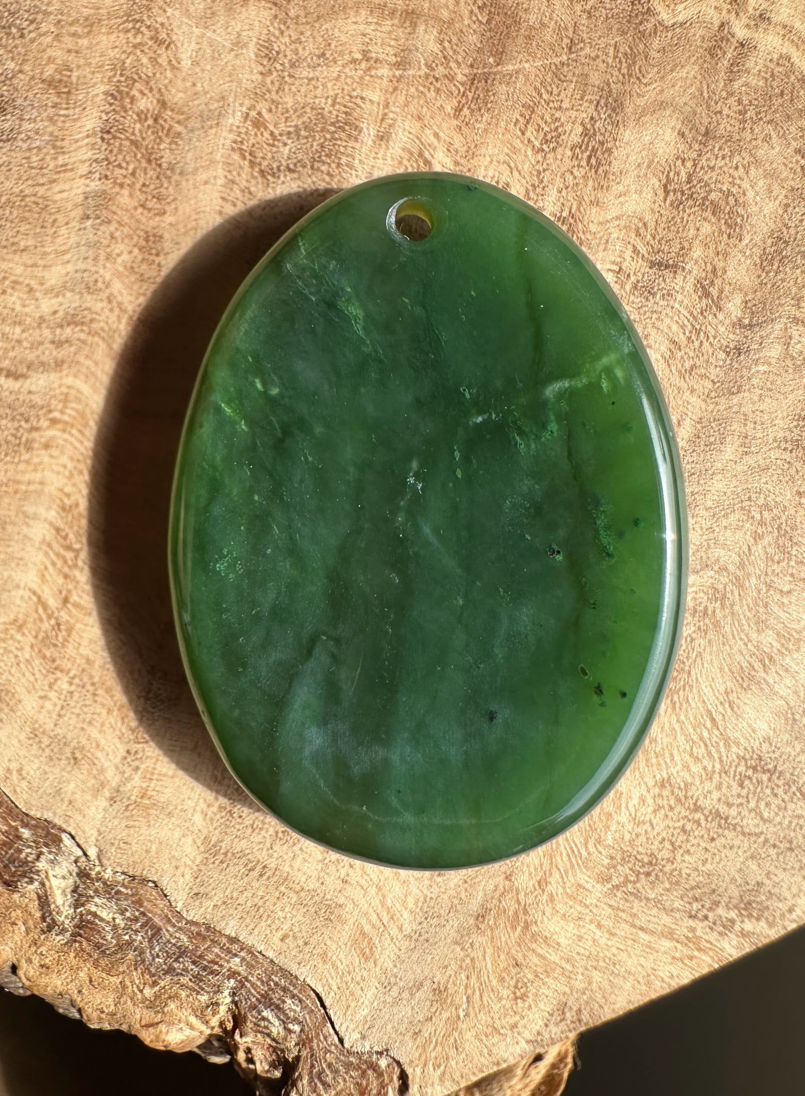 Green stone pendant on a wooden surface