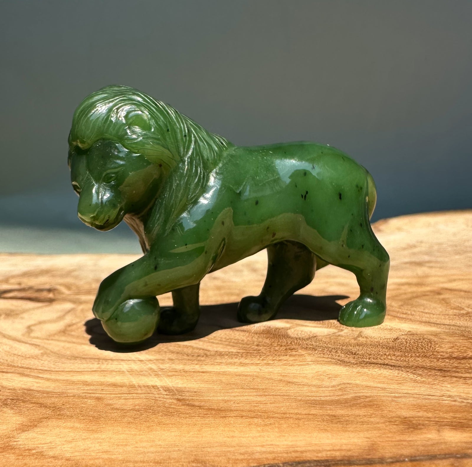 Green jade lion figurine standing with its front paw on a ball