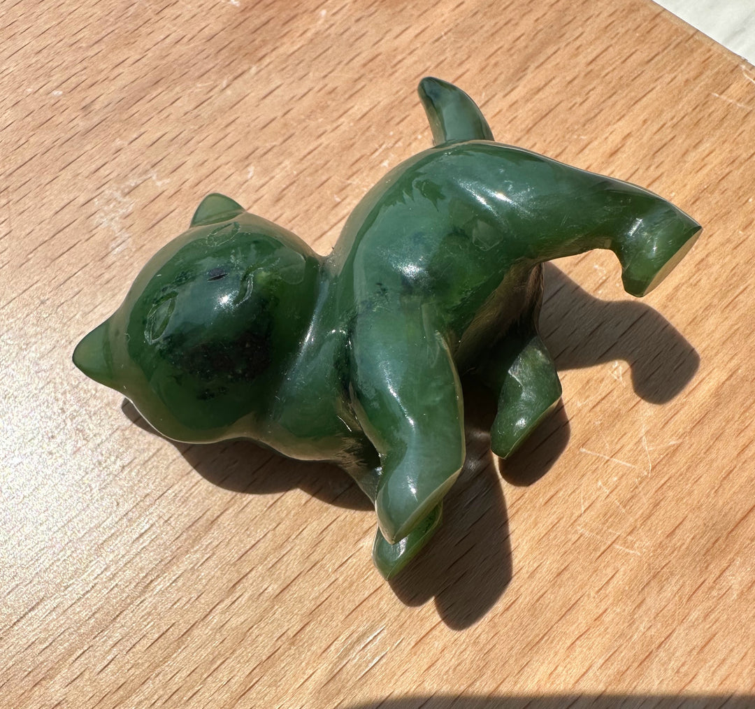 Canadian Jade 2 inch cat figurine in glossy green resting on a wooden surface