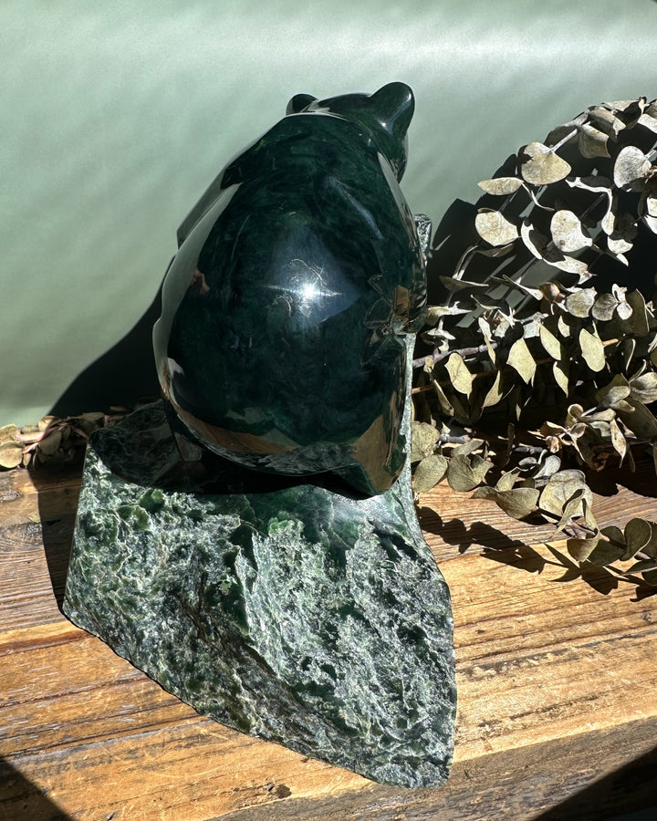 Dark green Ogden jade bear sculpture by Lyle Sopel resting on a rough rock base