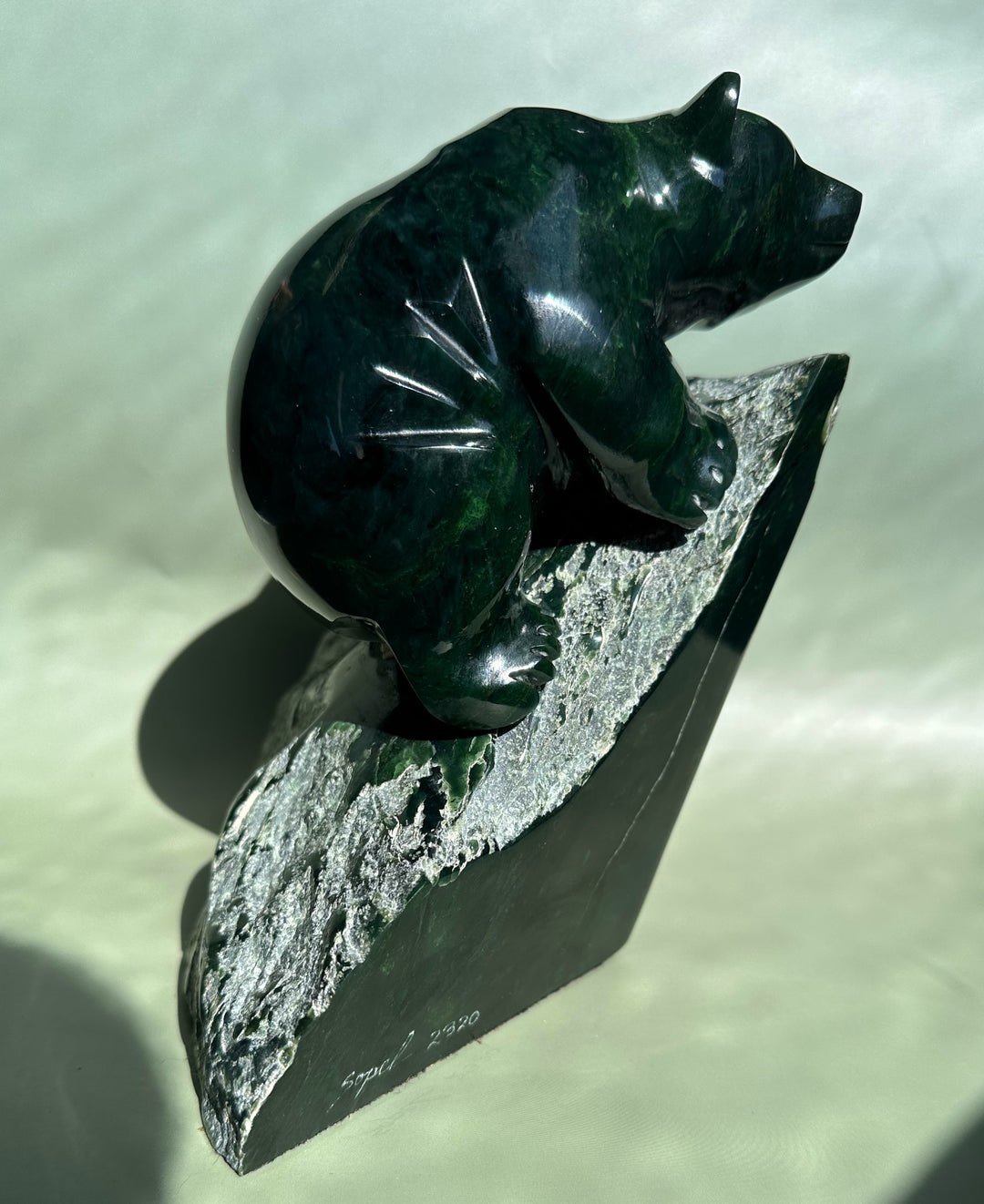 Dark Green Ogden Jade Bear by Lyle Sopel viewed from the side on a textured stone pedestal