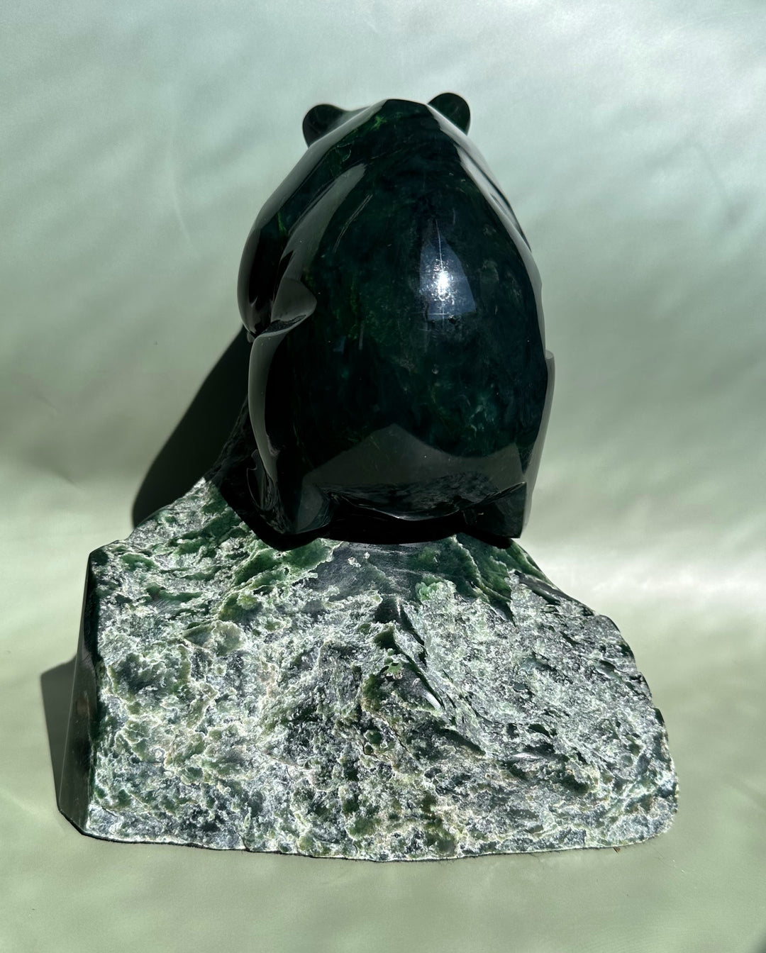 Back view of dark green Ogden jade bear sculpture by Lyle Sopel on a rough rock base