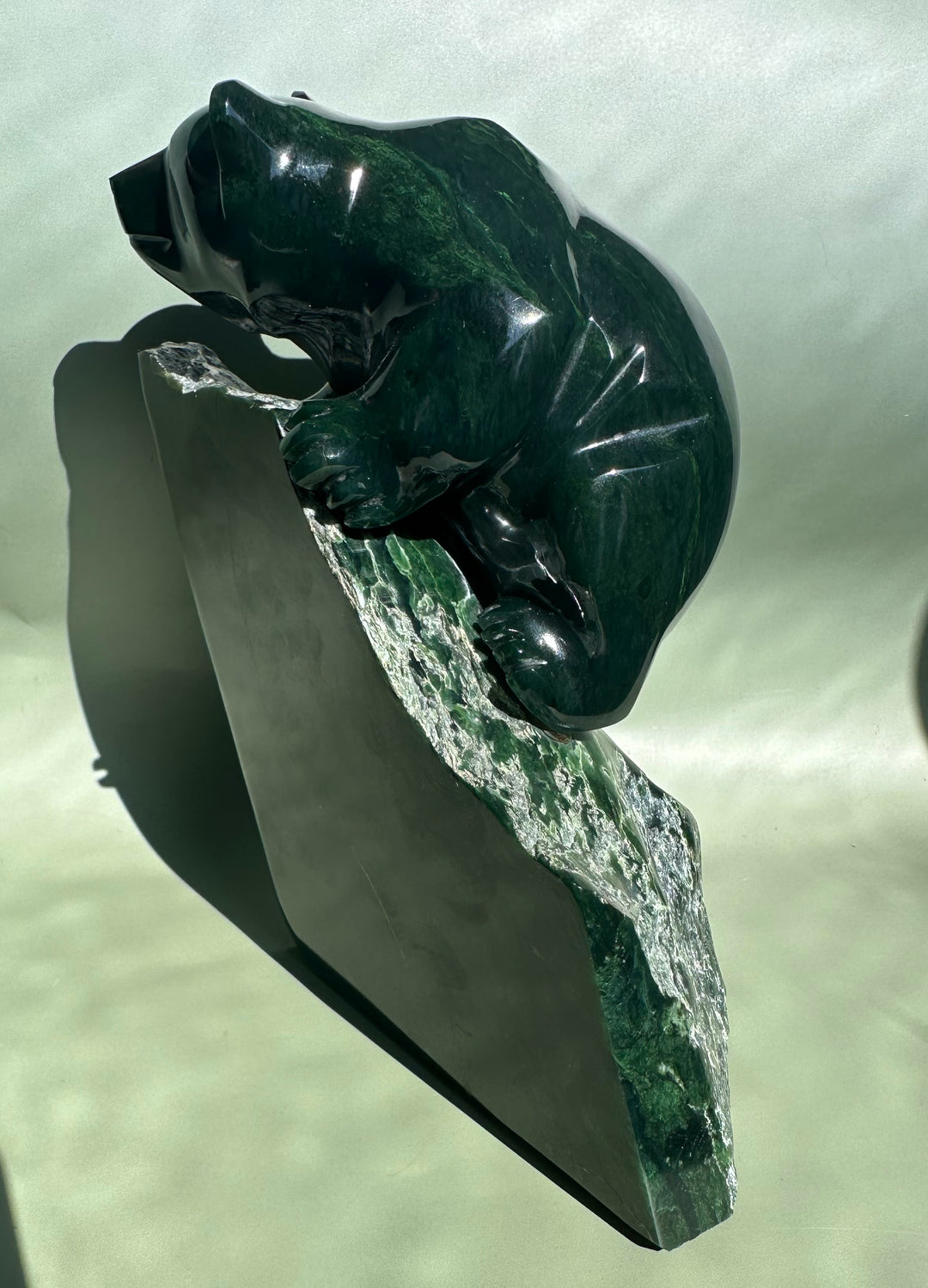 Dark Green Ogden Jade Bear by Lyle Sopel from an angled perspective atop a rough stone pedestal