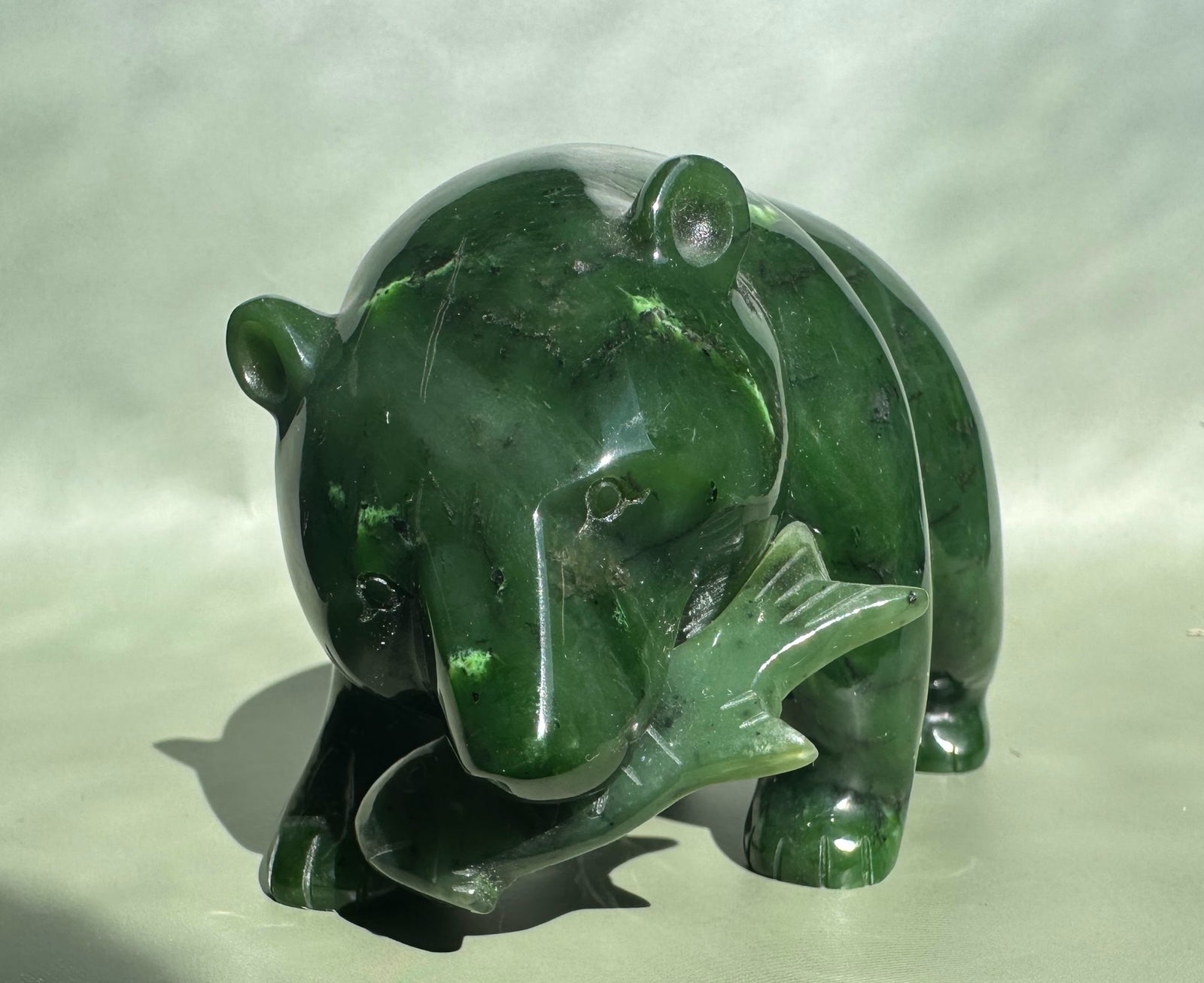 Side view of the Canadian Jade Bear showing its rounded back and paws in glossy green jade.