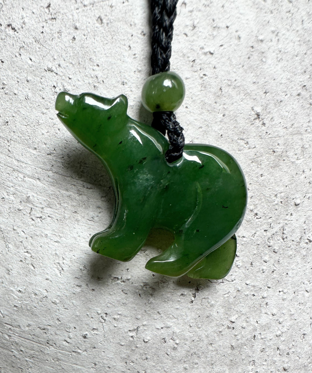 Green jade bear pendant on black cord with a small round bead above