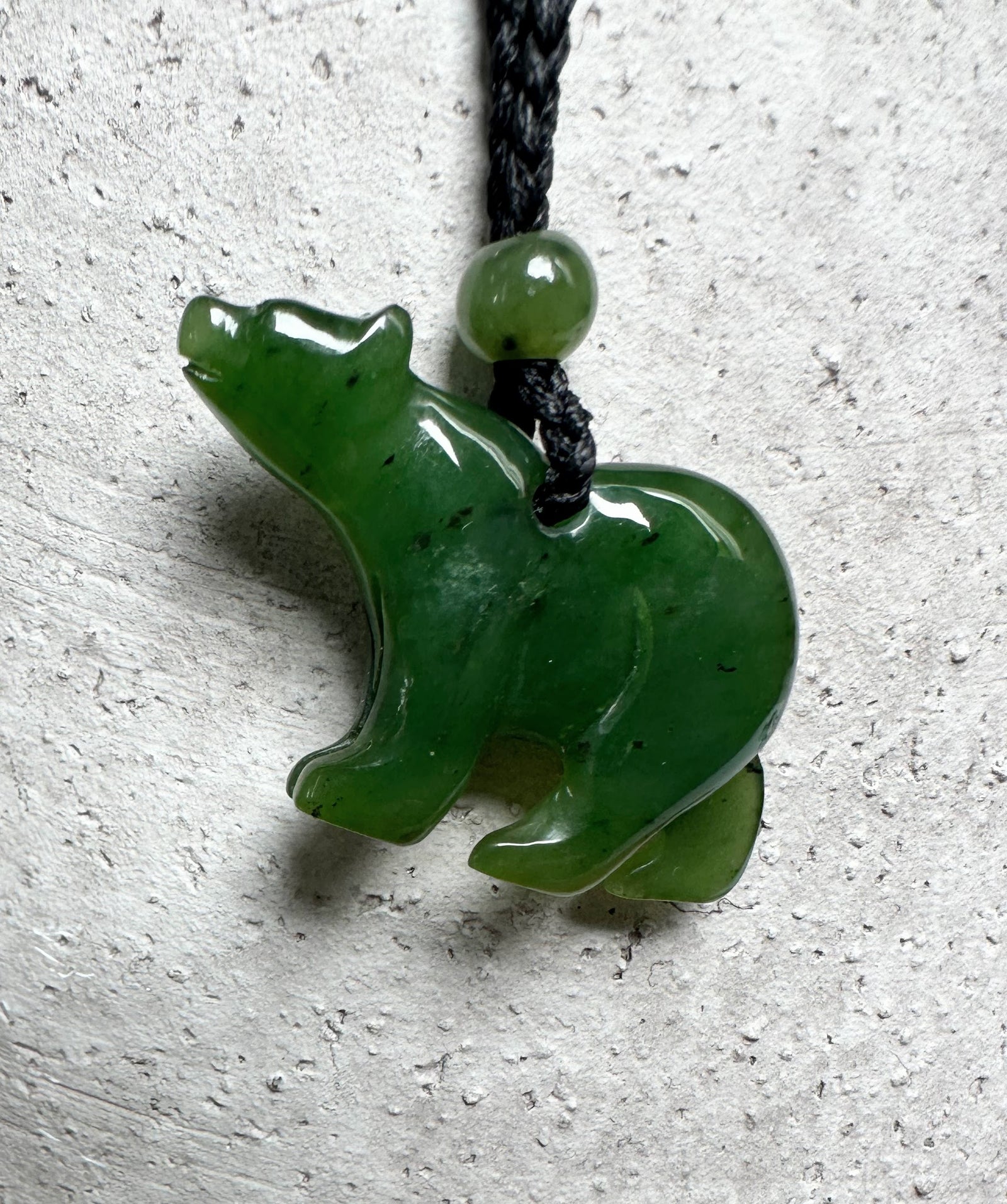 Green jade bear pendant on black cord with a small round bead above
