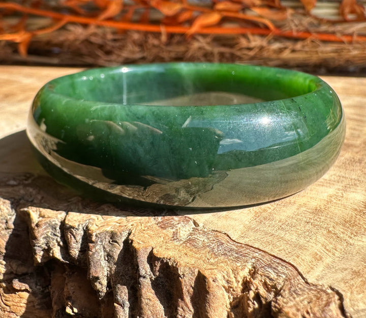 Canadian Jade Bangle 54 x 17mm on weathered wood with orange pine needles in background.