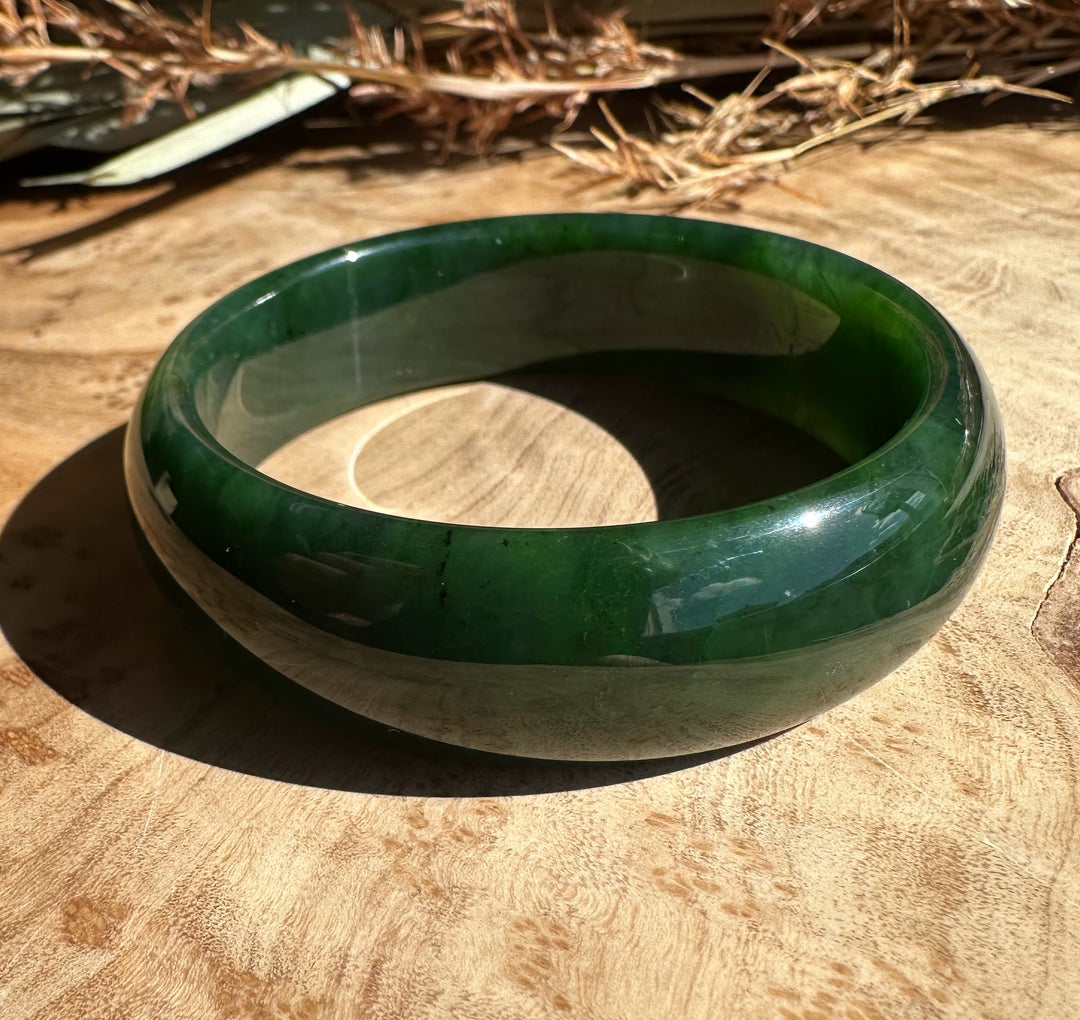 Canadian jade bangle on wood surface, 54 x 17mm
