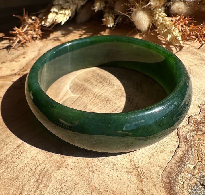 Canadian jade bangle 54 x 17mm shown on a wooden surface with dried plants