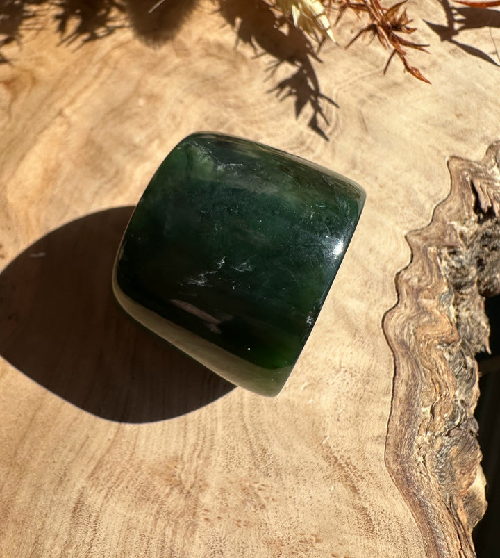 Canadian Ogden Jade Thumb Ring size 13 with a dark to light green gradient on a wooden surface.