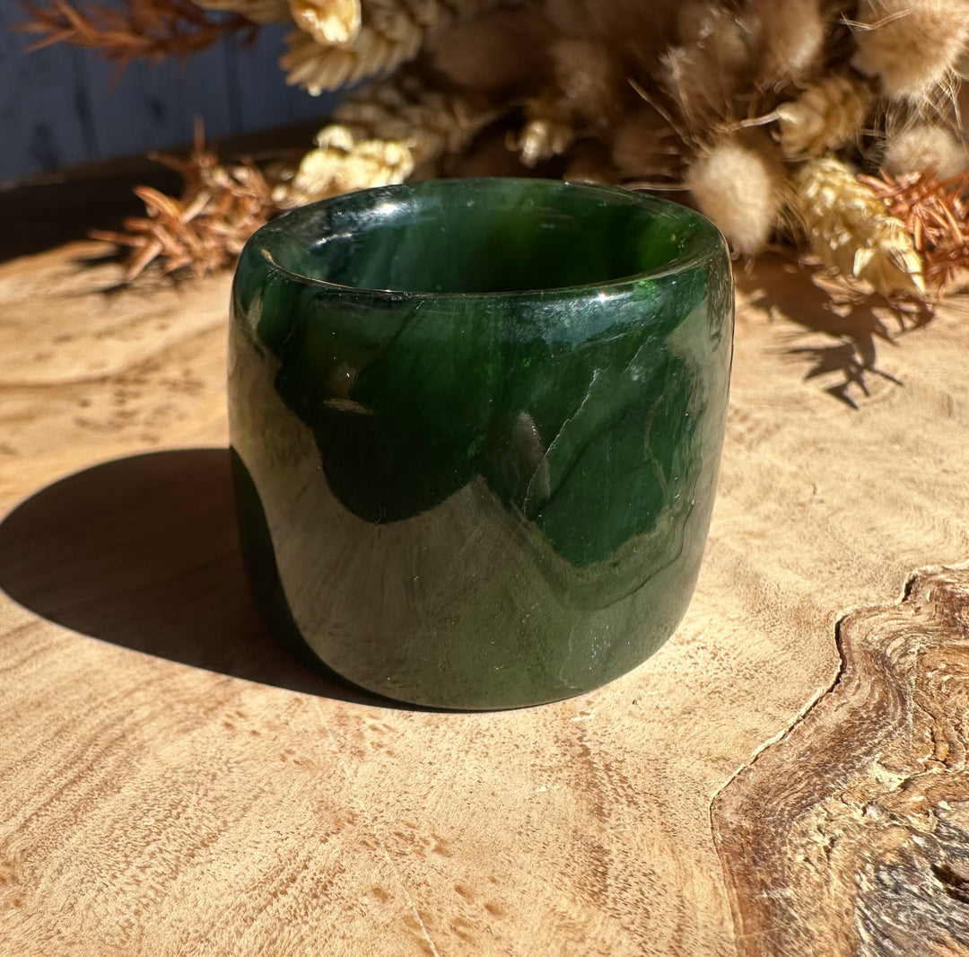 Canadian Ogden Jade Thumb Ring size 13 in glossy deep green jade resting on a wooden surface