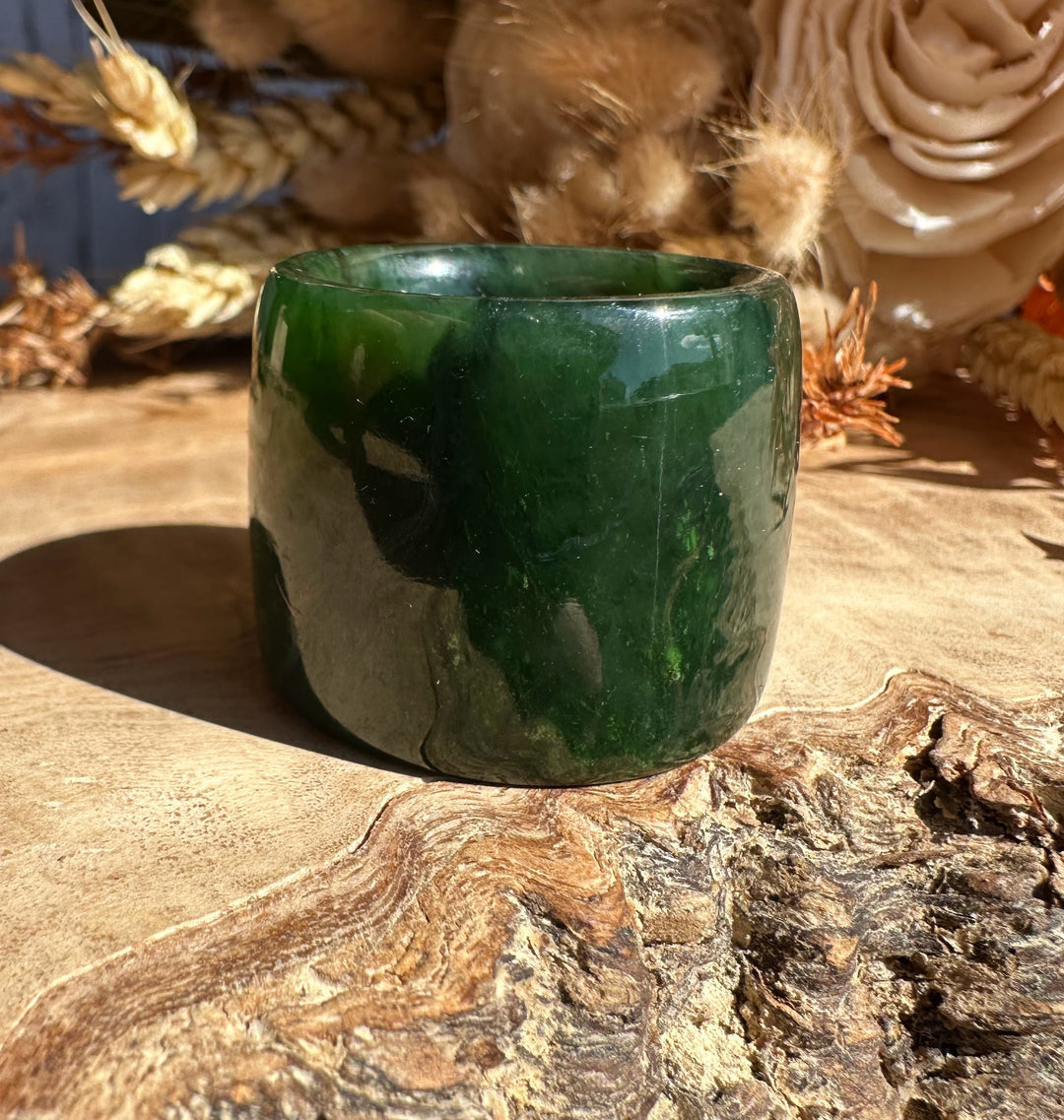 Canadian Ogden Jade Thumb Ring size 13 in glossy green jade shown from a slight front angle on wood