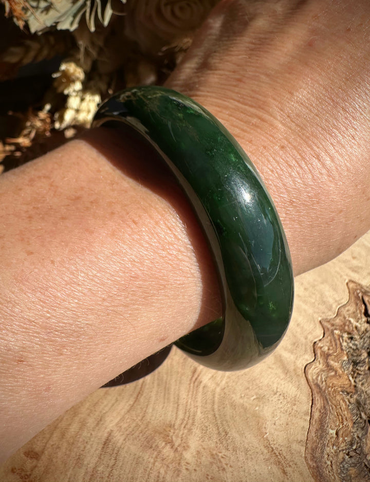 Canadian Jade Bangle worn on the wrist with deep green marbling, close-up