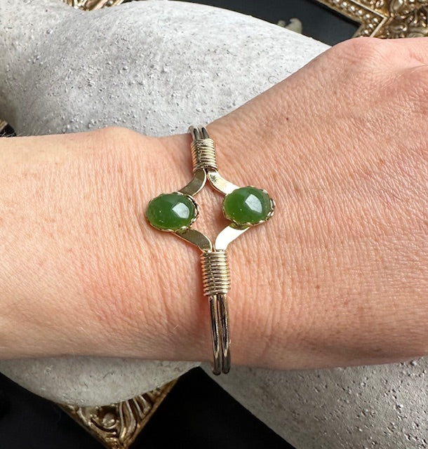 Vintage jade bracelet with two green cabochons in a silver setting on a wrapped cuff worn on the wrist