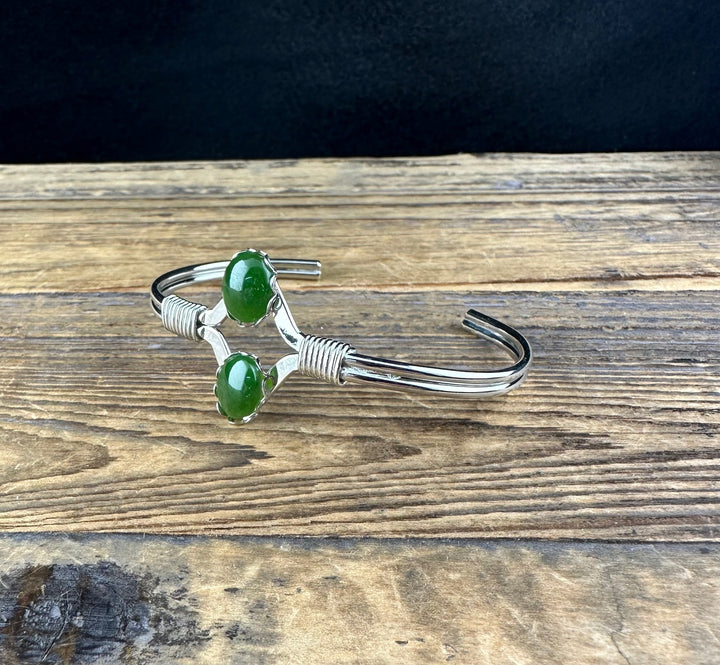 Side view of vintage Jade Bracelet showing two green stones and wire wrapped detailing on a silver cuff.