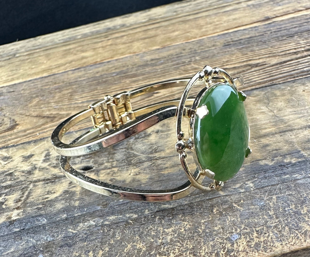 Vintage jade bracelet featuring a large oval green jade cabochon in an ornate silver bezel on a slim double band.