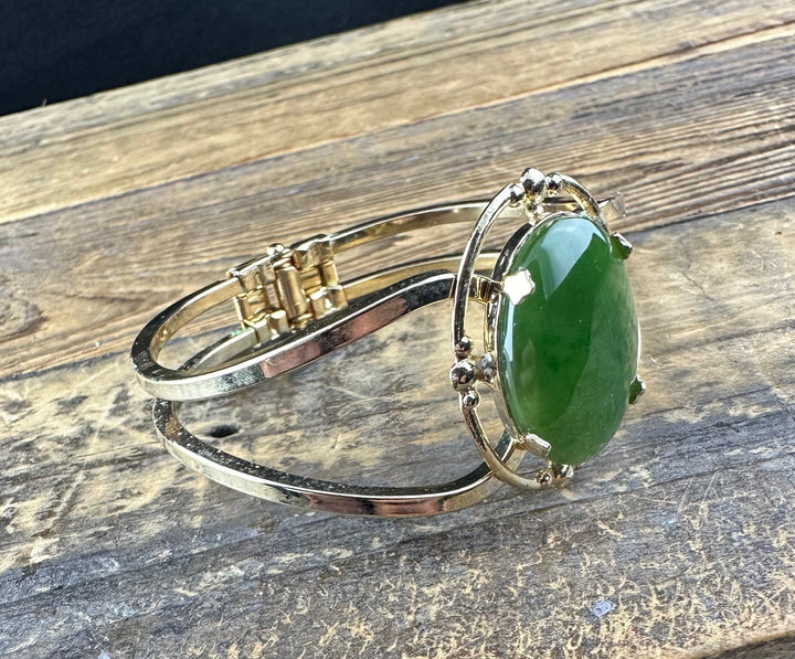 Vintage jade bracelet featuring a large oval green jade cabochon in an ornate silver bezel on a slim double band.