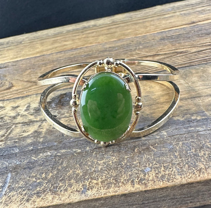 Vintage bracelet with a large oval green jade cabochon in a decorative gold and silver bezel on a curved band.