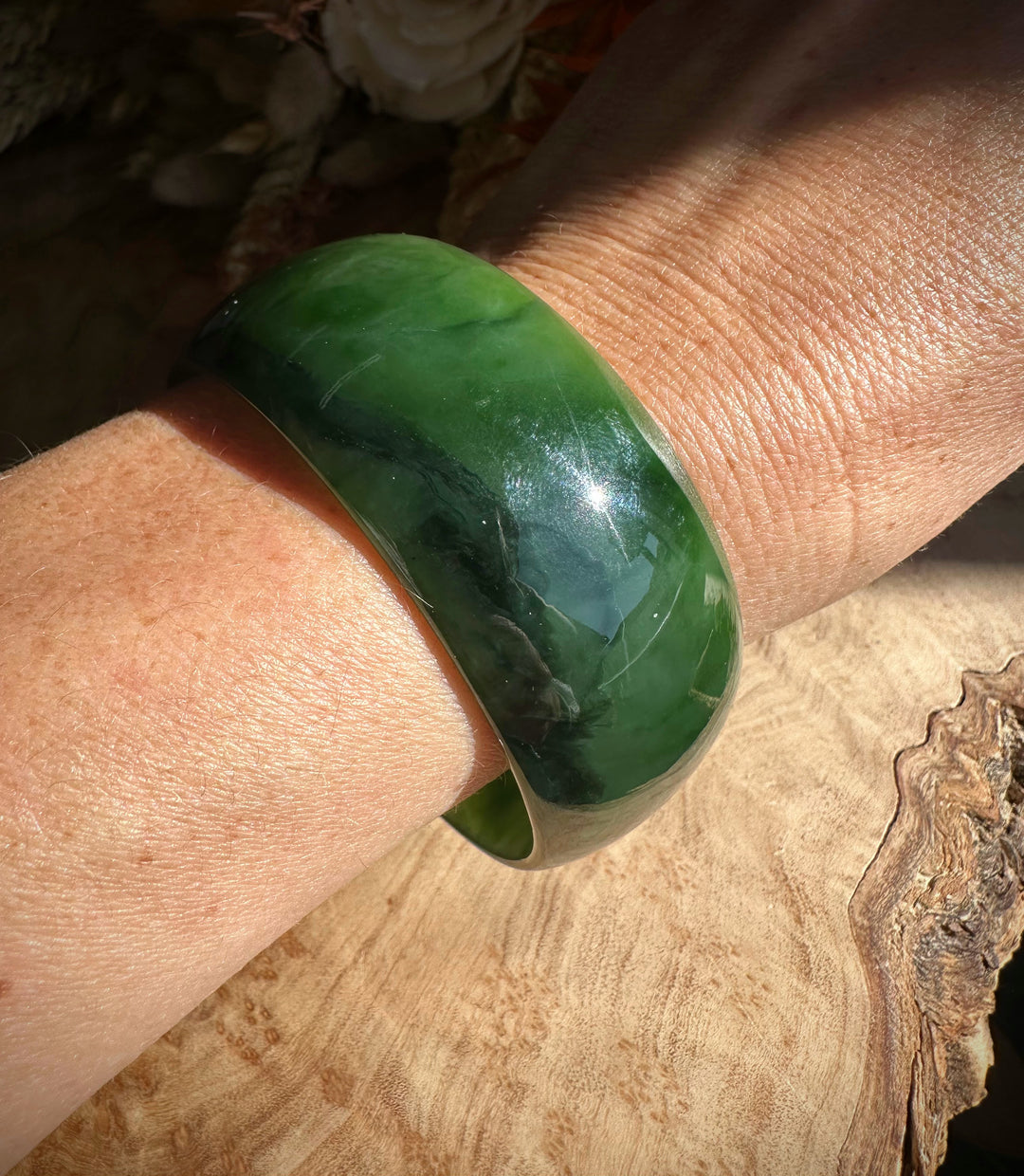 A Grade Ogden Jade Bangle on the wrist with dark green marbling and a glossy finish