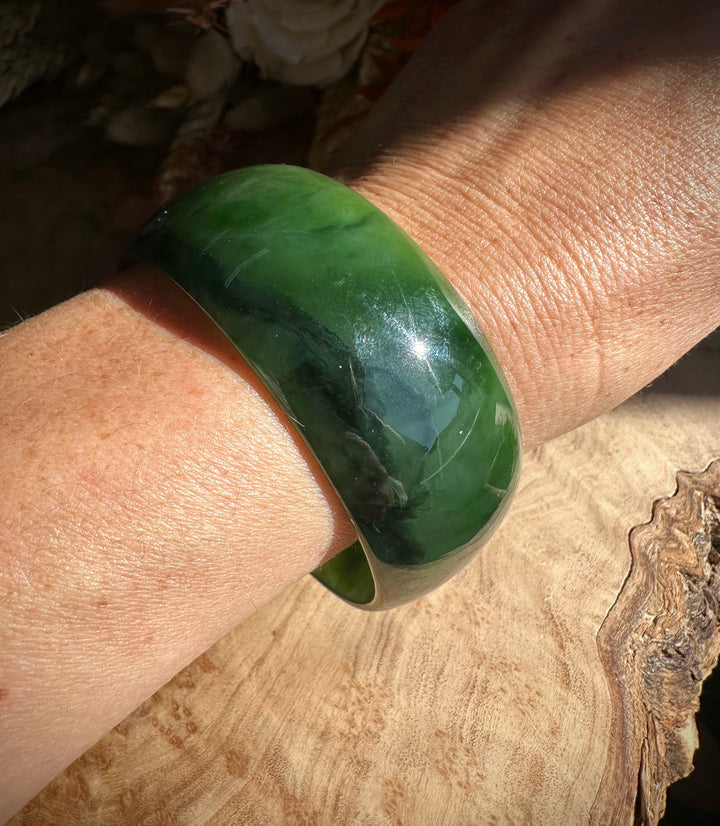 A Grade Ogden Jade Bangle on the wrist with dark green marbling and a glossy finish