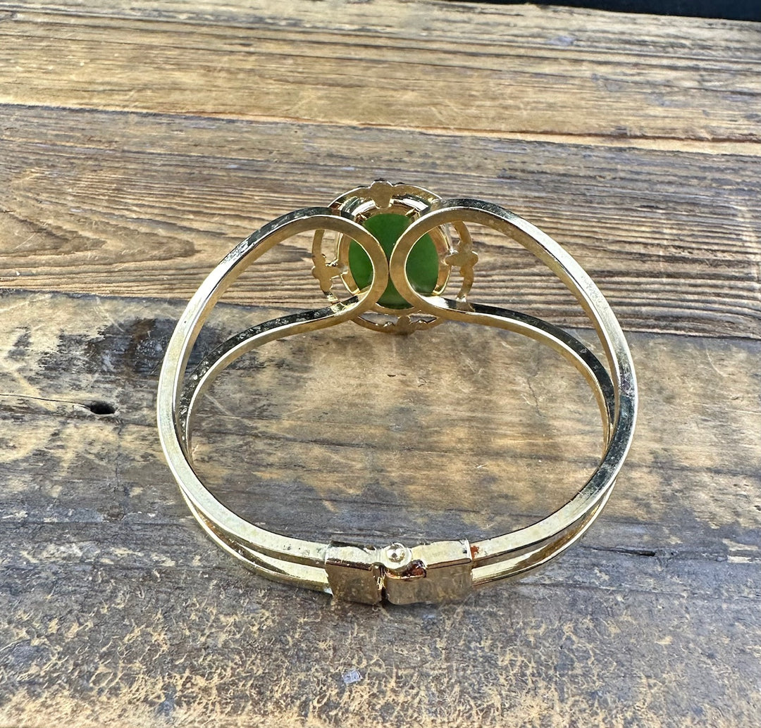 Vintage Jade Bracelet with a green jade cabochon and gold filigree setting on wood surface