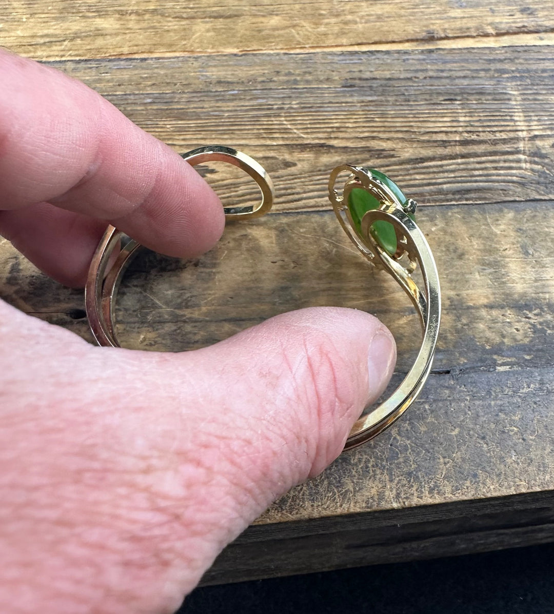 Hand holds Vintage Jade Bracelet showing the green jade cabochon and the gold band