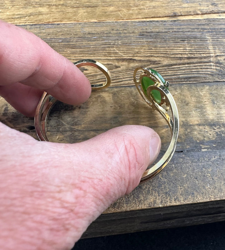 Hand holds Vintage Jade Bracelet showing the green jade cabochon and the gold band