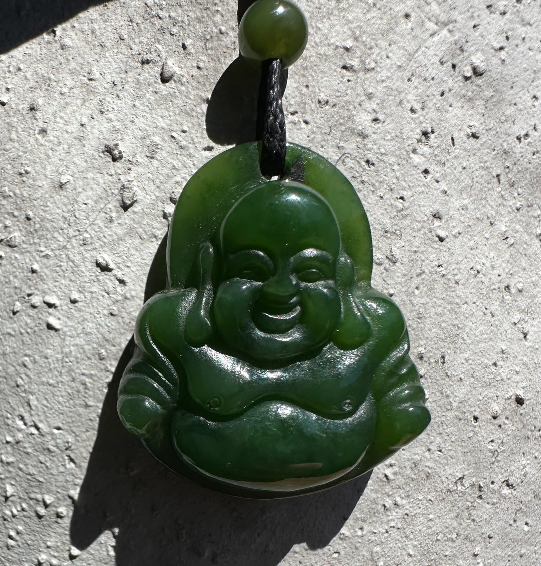 Front view of a green jade Laughing Buddha pendant with carved details on a black cord
