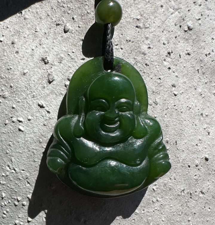 Front view of a green jade Laughing Buddha pendant with carved details on a black cord