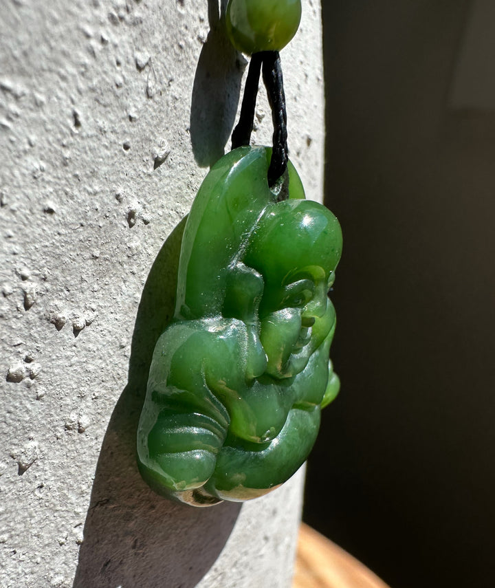 Green jade Happy Buddha pendant 26mm shown in profile on cord