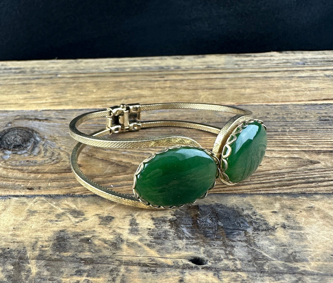 Vintage bracelet with two oval green jade stones set side by side in a gold-toned band with scalloped bezels.