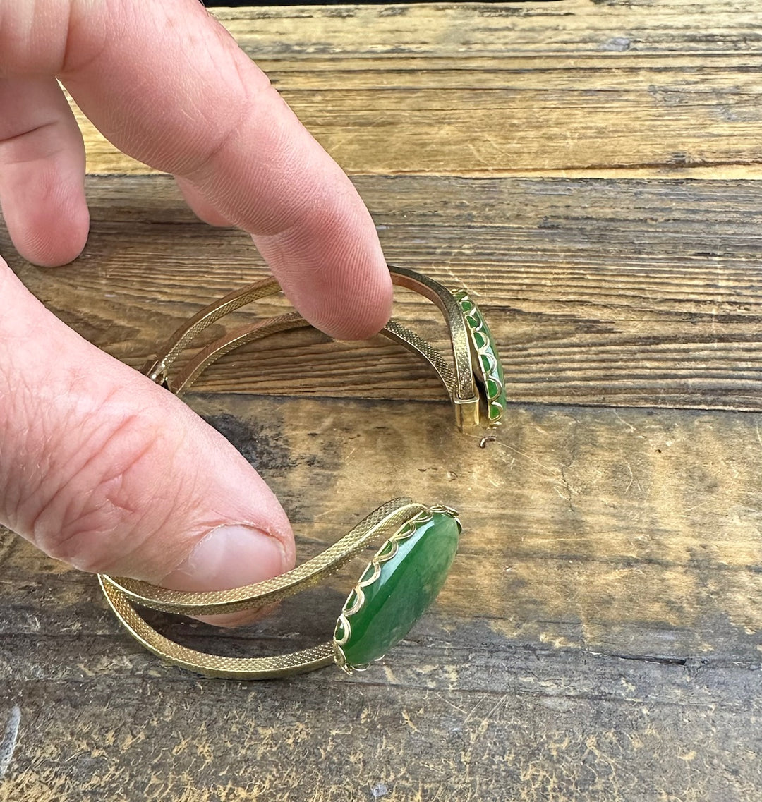 Close up of the gold tone vintage jade bracelet with a green oval jade cabochon and scalloped bezel.