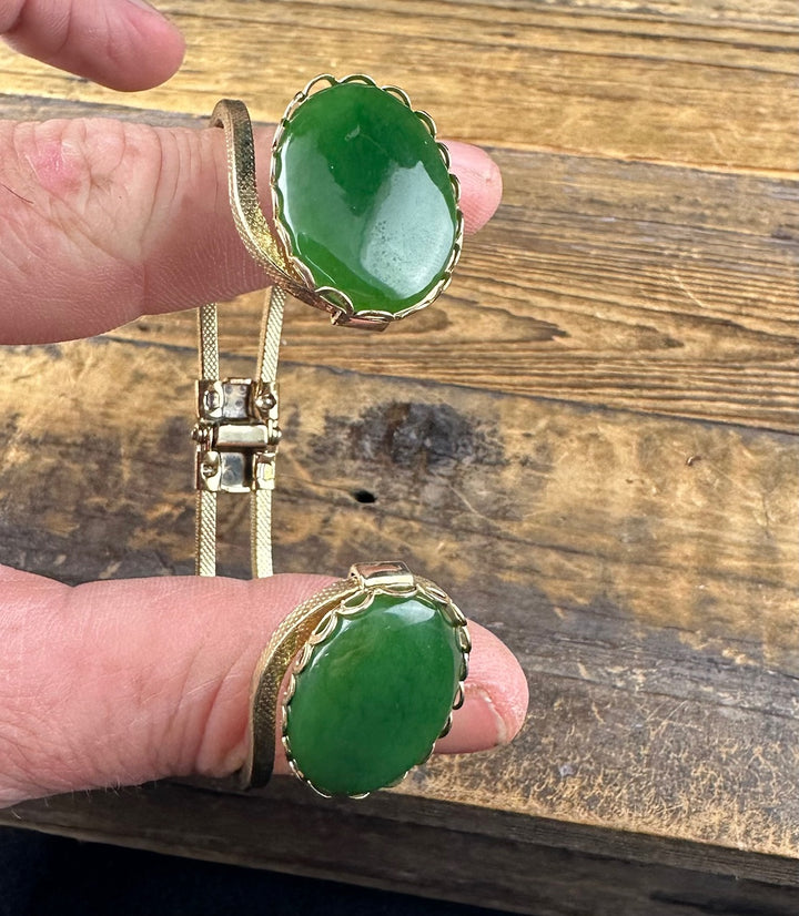Close up of vintage jade bracelet showing a large green jade cabochon set in a scalloped gold bezel.