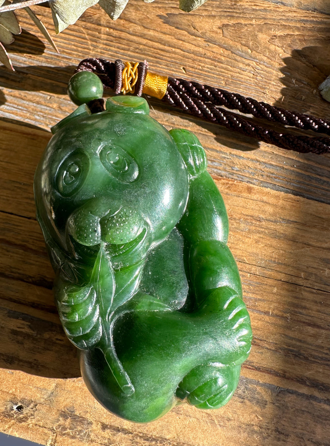 Panda shaped jade pendant in dark green with a round bail and braided cord.