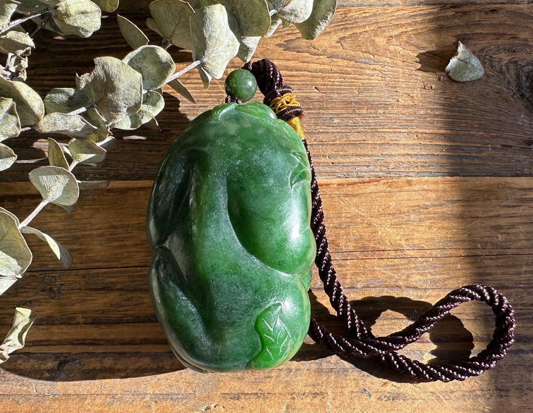 Green jade Panda Pocket Pendant with braided cord on rustic wood