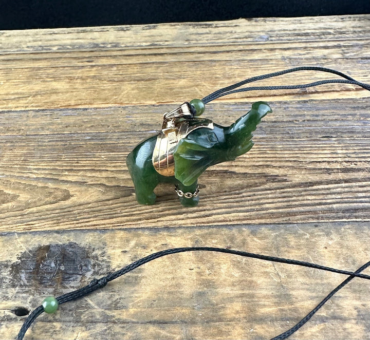 Vintage Jade Elephant Pendant displayed on wood with cord and a small green bead along the string.