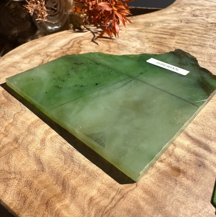 Siberian nephrite jade slab on a wood surface with a white label reading SIBERIAN